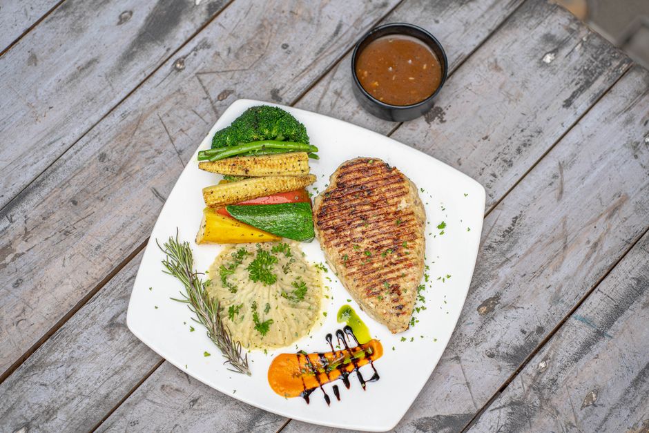 Chicken breast with roasted vegetables plated on a rustic table